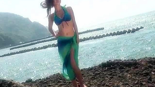 Modelo asiática pelirroja y sumisa posando en la playa